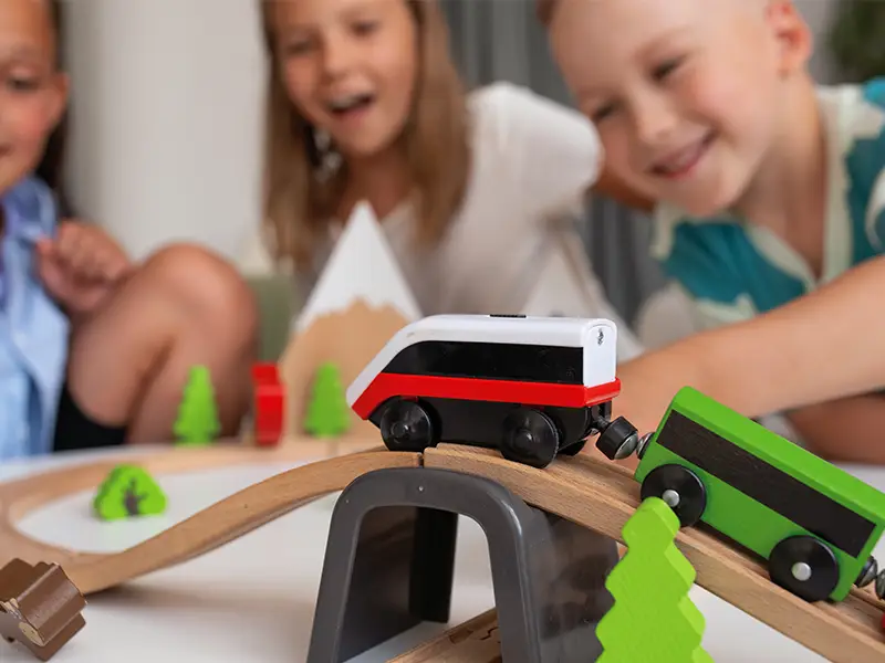 Children smiling and playing together with a wooden toy train set