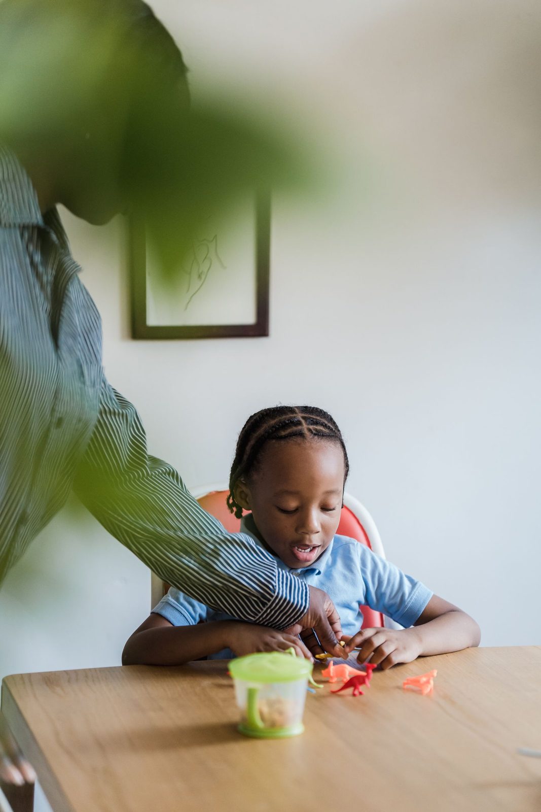 Smiling young girl stacking small blocks at a table while an adult works with her