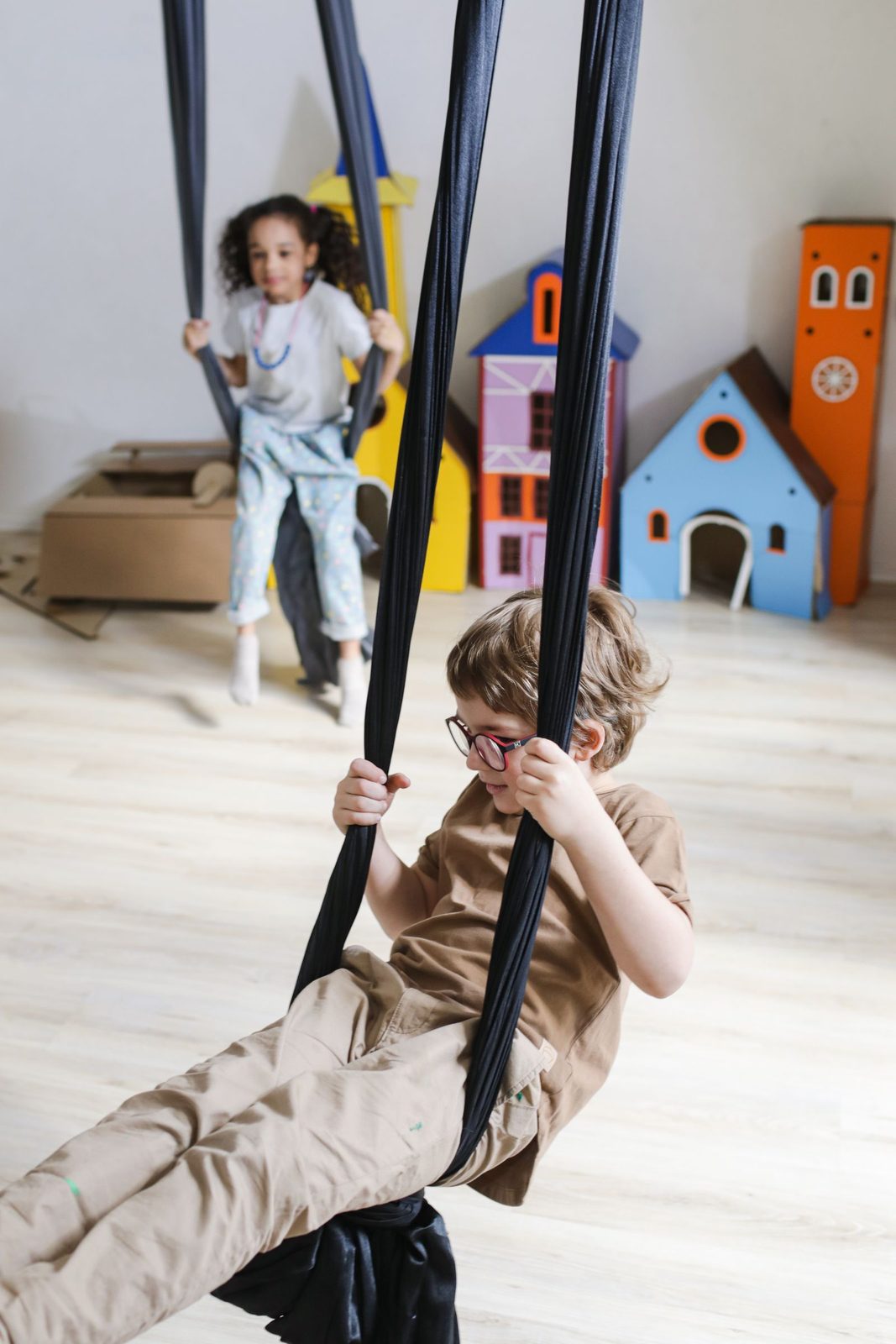 Child playing on a fabric sensory swing in a bright indoor playroom